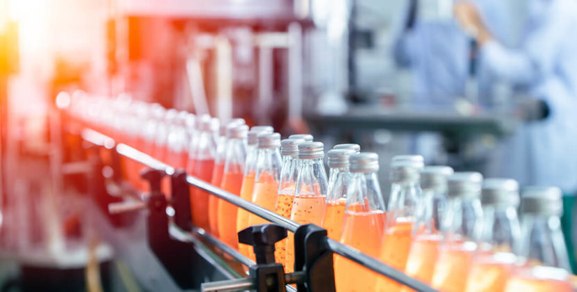 refrigerantes de cor laranja enfileirados em linha de produção de bebidas