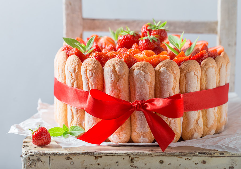 bolo de morangos e geleia feito em uma padaria boutique envolto em biscoitos champanhe e preso por um laço vermelho