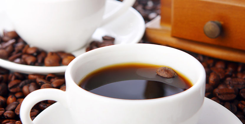 Fotografia de uma xicara e grãos de café, ilustrando o processo de agregação de valor às embalagens do café nacional.