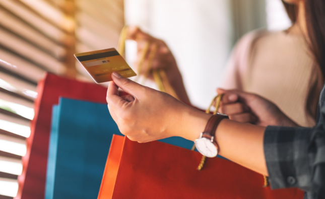 Foto de uma pessoa segurando pacotes de compra e um cartão, representando o processo de conquista do consumidor.