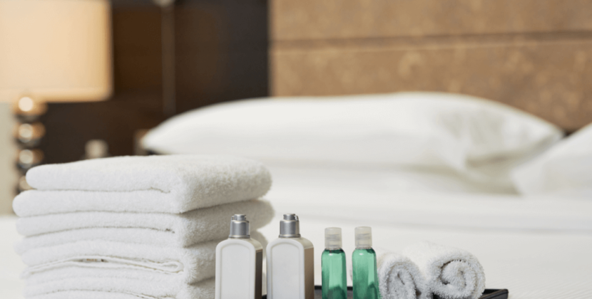 Foto de diferentes embalagens de produtos de higiene em cima de uma cama de hotel, representando as oportunidades do mercado de terceirização de cosméticos.