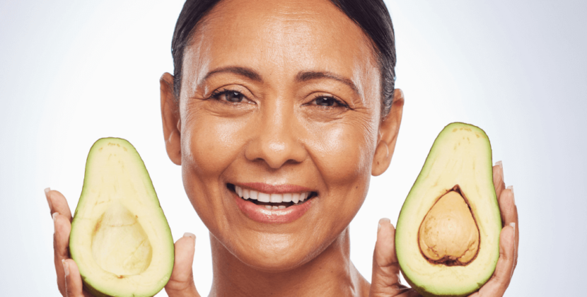 Imagem de uma mulher de pele saudável sorrindo enquanto segura metade de um coco, ilustrando os benefícios dos alimentos funcionais para a saúde e a estética.