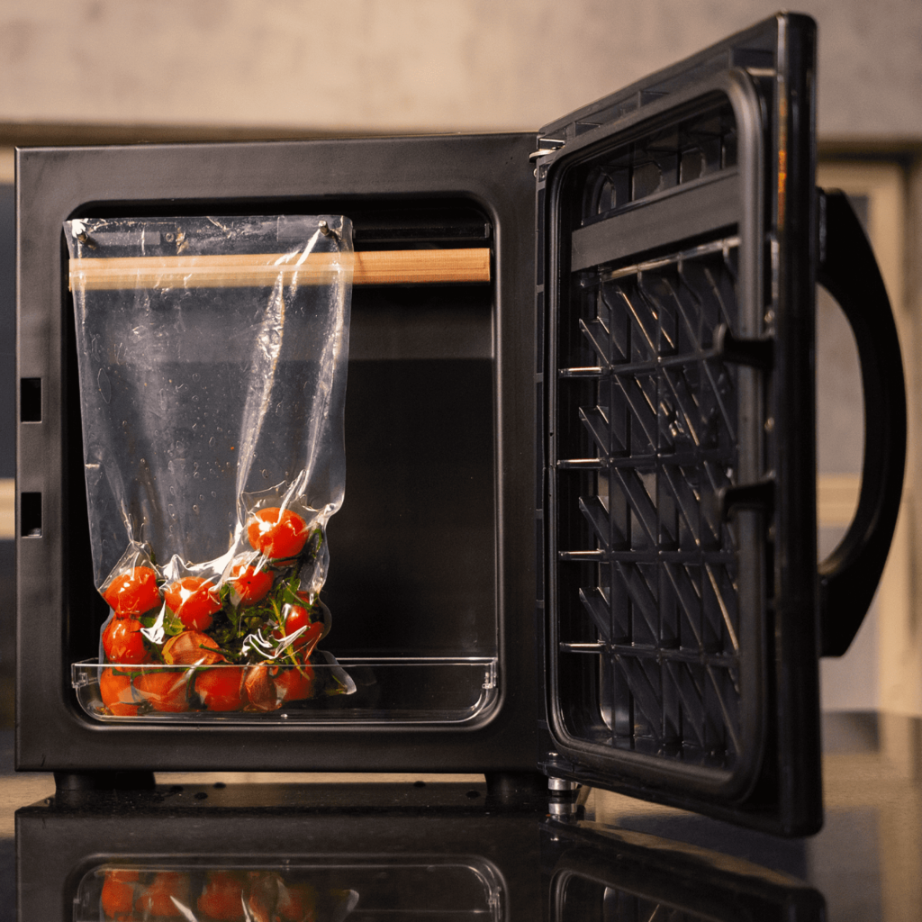 Fotografia da Seladora a Vácuo Vertical Suprême Vac Vertical e Horizontal CCVS S-250 V M com um saco de tomates cerejas dentro de sua câmara