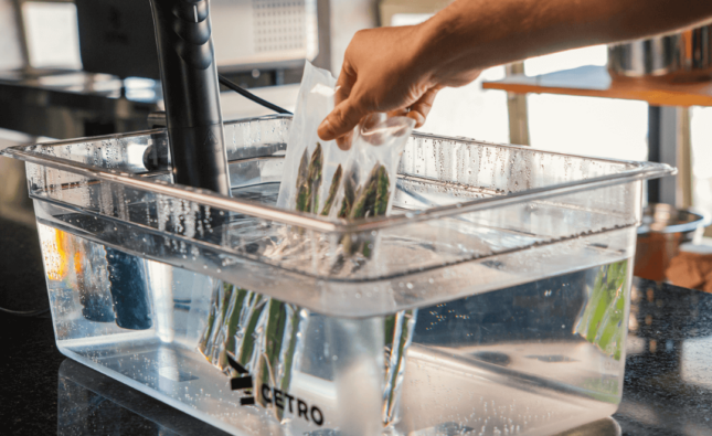 Imagem de aspargos selados a vácuo sendo colocados em uma cuba com água com um Termocirculador Sous Vide da Cetro.