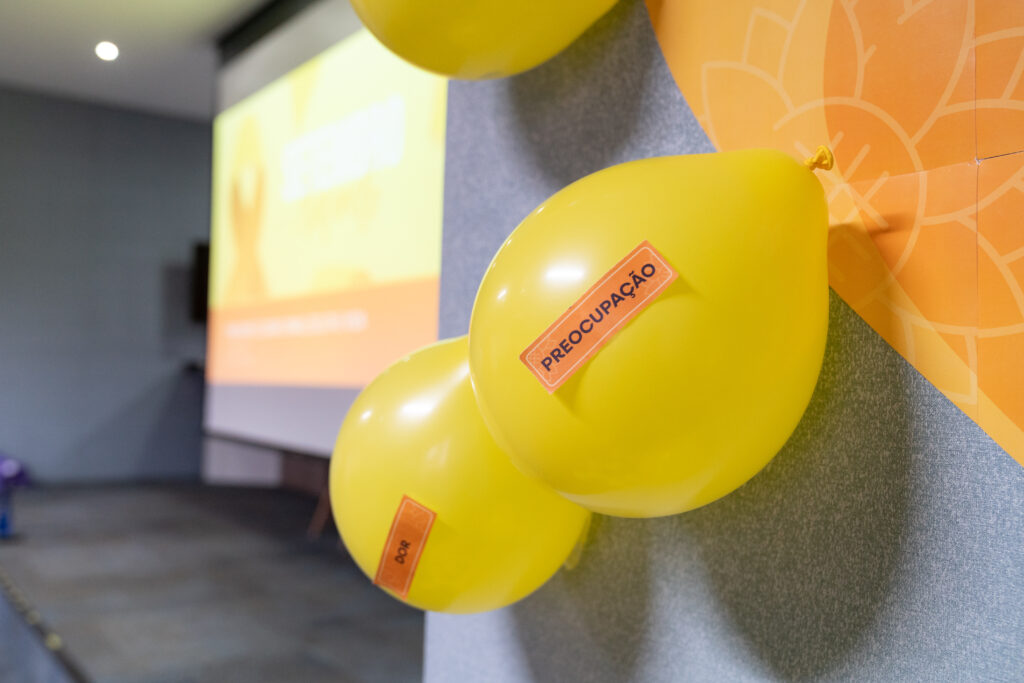 Fotografias dos balões amarelos da dinâmica da Campanha de Setembro Amarelo, de um colaborador estourando um balão e das velas aromáticas.