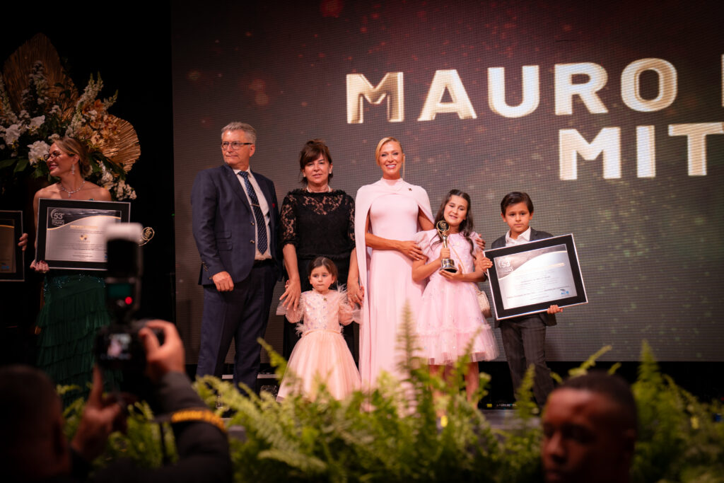 Fotografias da família de Léo Mello recebendo o prêmio no palco e dos colaboradores da Cetro e seus cônjuges que compareceram ao evento.