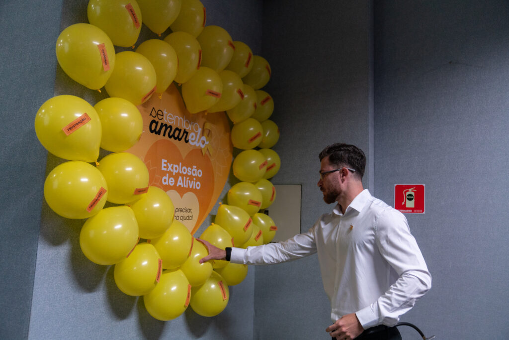 Fotografias dos balões amarelos da dinâmica da Campanha de Setembro Amarelo, de um colaborador estourando um balão e das velas aromáticas.