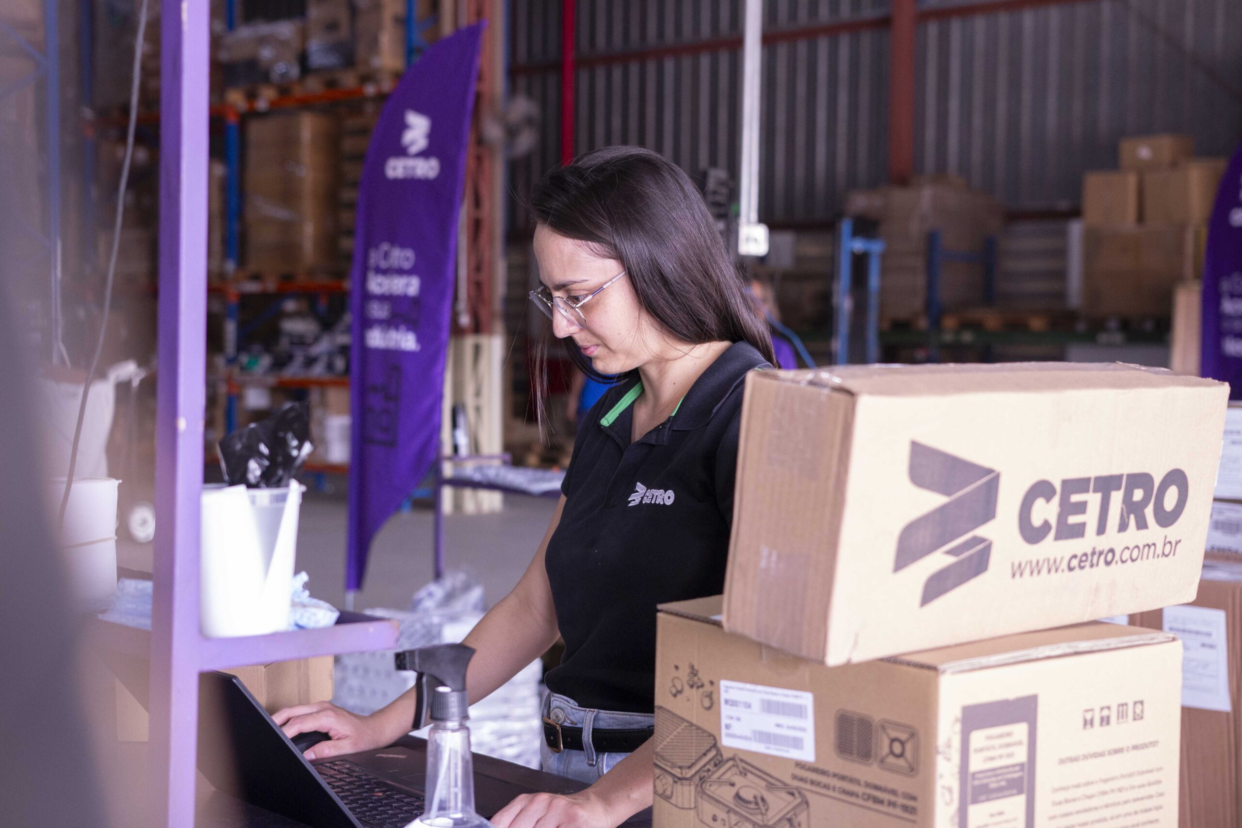 Fotografias da equipe logística da Cetro e de banners da campanha Acelera Black 2025 no Centro de Distribuição da companhia.