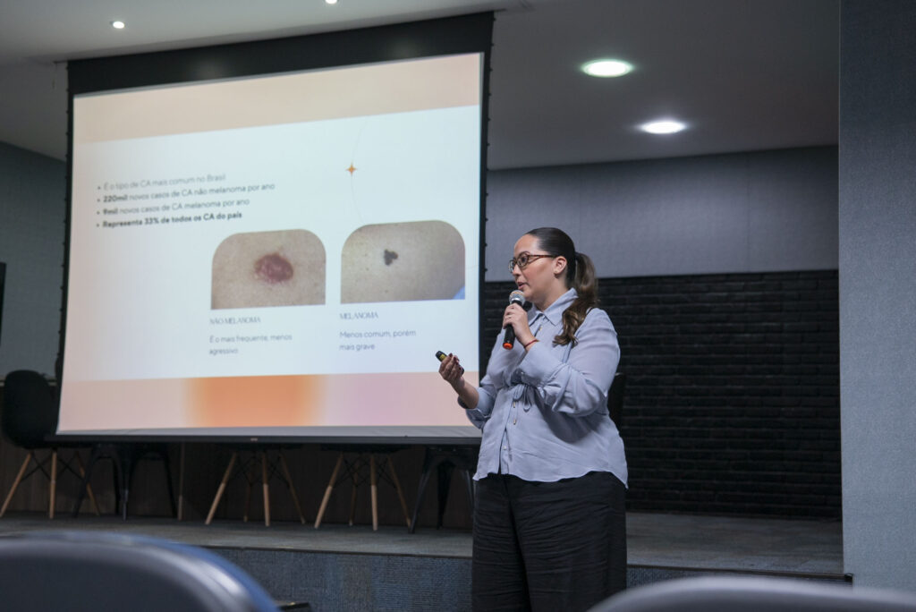 Fotografia das palestrantes falando sobre a Campanha Dezembro Laranja e dos colaboradores assistindo.