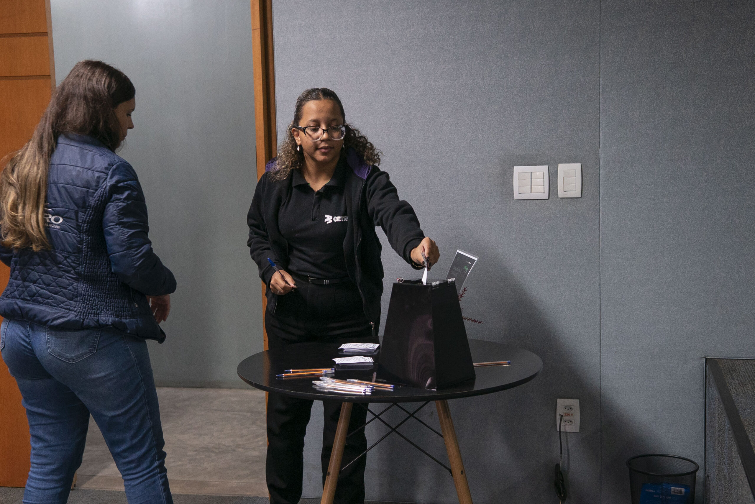 Fotografias de colaboradores participando da votação e da urna para depósito das cédulas da eleição da CIPA 2026.