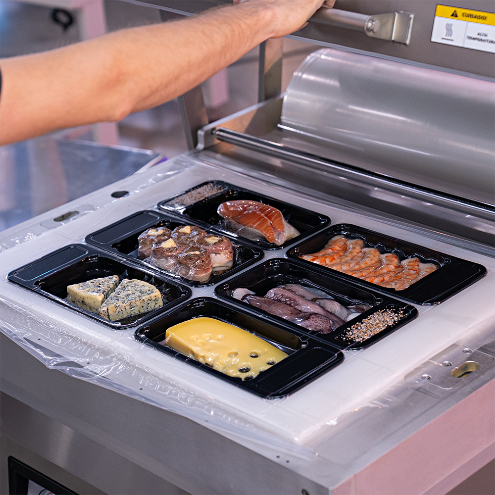 Fotografias de um operador utilizando a Seladora a Vácuo de Bandeja de Plataforma MV-SKINPACK CTVS 760 SP para embalar diferentes alimentos a vácuo em bandejas.