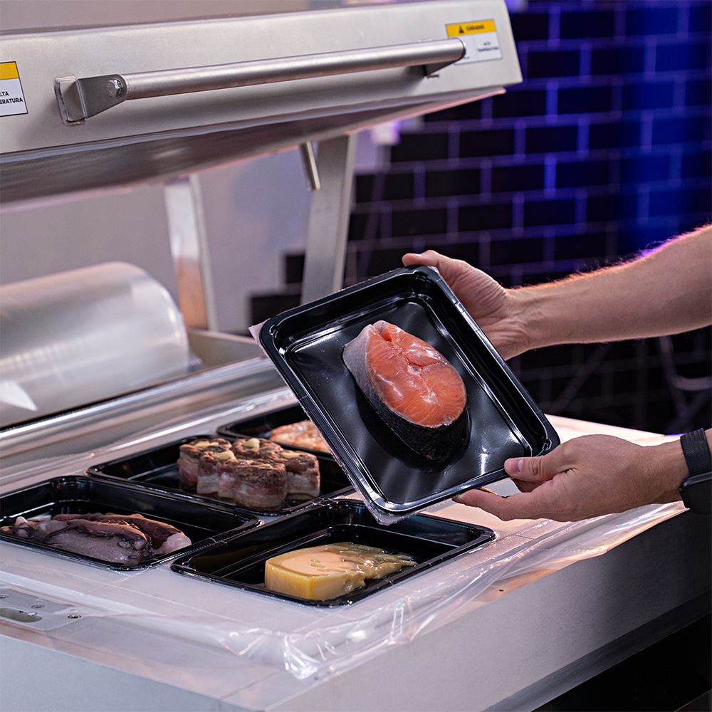 Fotografias de um operador utilizando a Seladora a Vácuo de Bandeja de Plataforma MV-SKINPACK CTVS 760 SP para embalar diferentes alimentos a vácuo em bandejas.