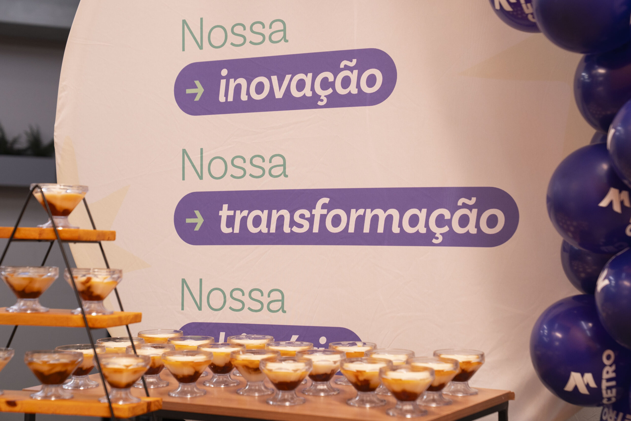 Fotografias do expositor da Cetro escrito “Nossa inovação, nossa transformação, nossa história” e de uma panela de arroz com legumes cortados no formato da escrita “Cetro 14”, representando o aniversário da companhia.