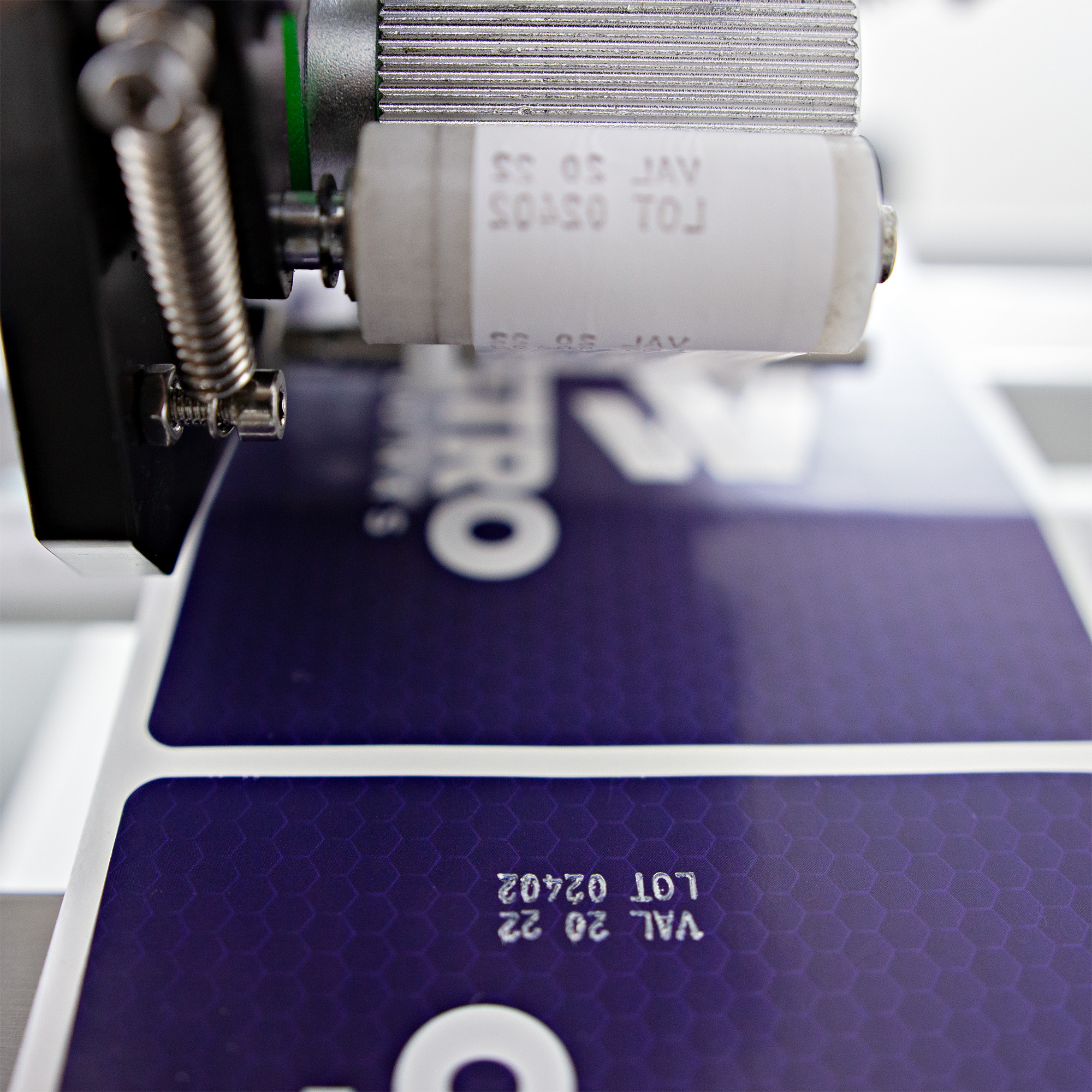 Fotografias de adesivos roxos com o logotipo da Cetro, com informações impressas pelo datador de termotransferência da Rotuladora Semiautomática com Datador CSLM DP.