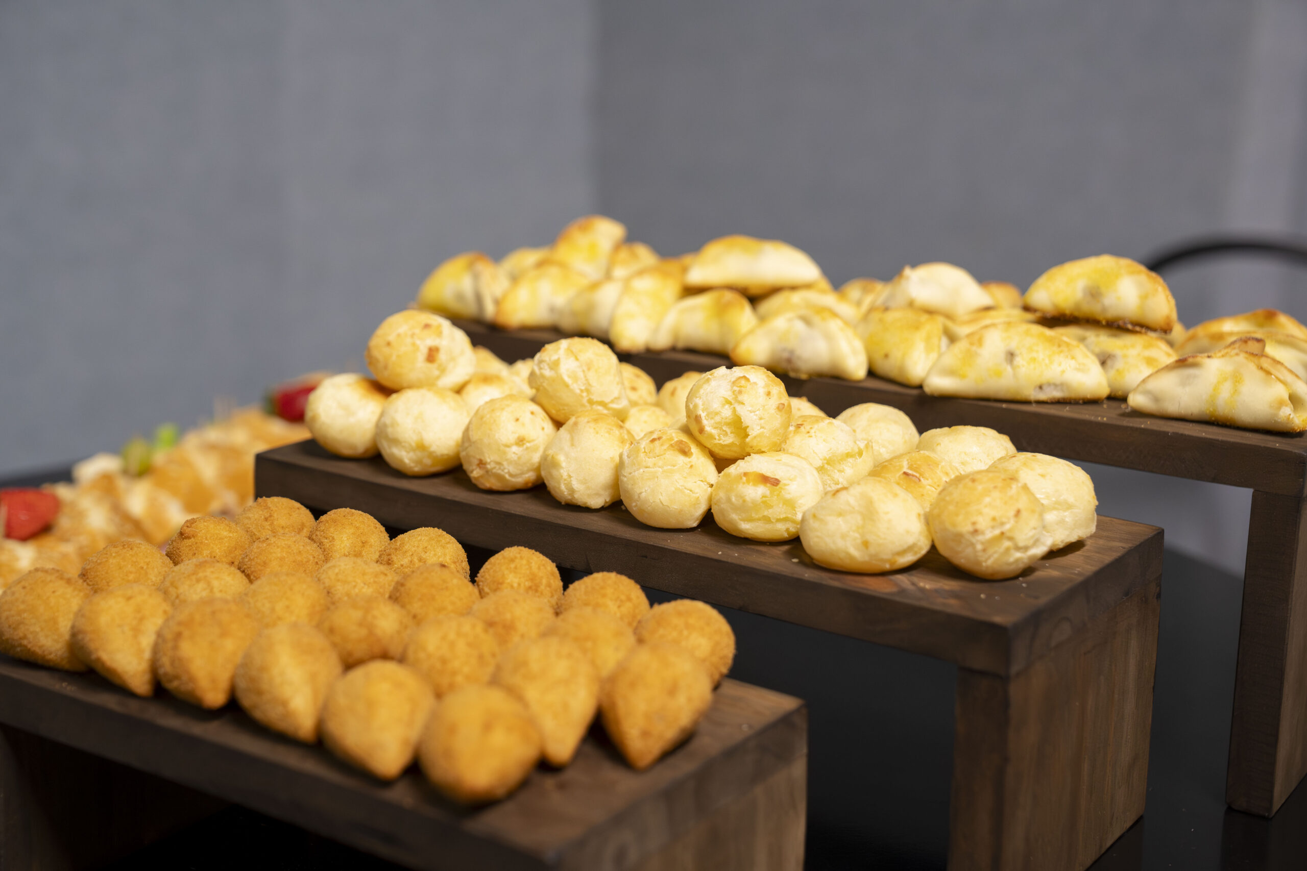 Fotografias dos alimentos expostos na mesa para o coffee break e de uma colaboradora Cetro em frente ao telão de apresentação do treinamento.