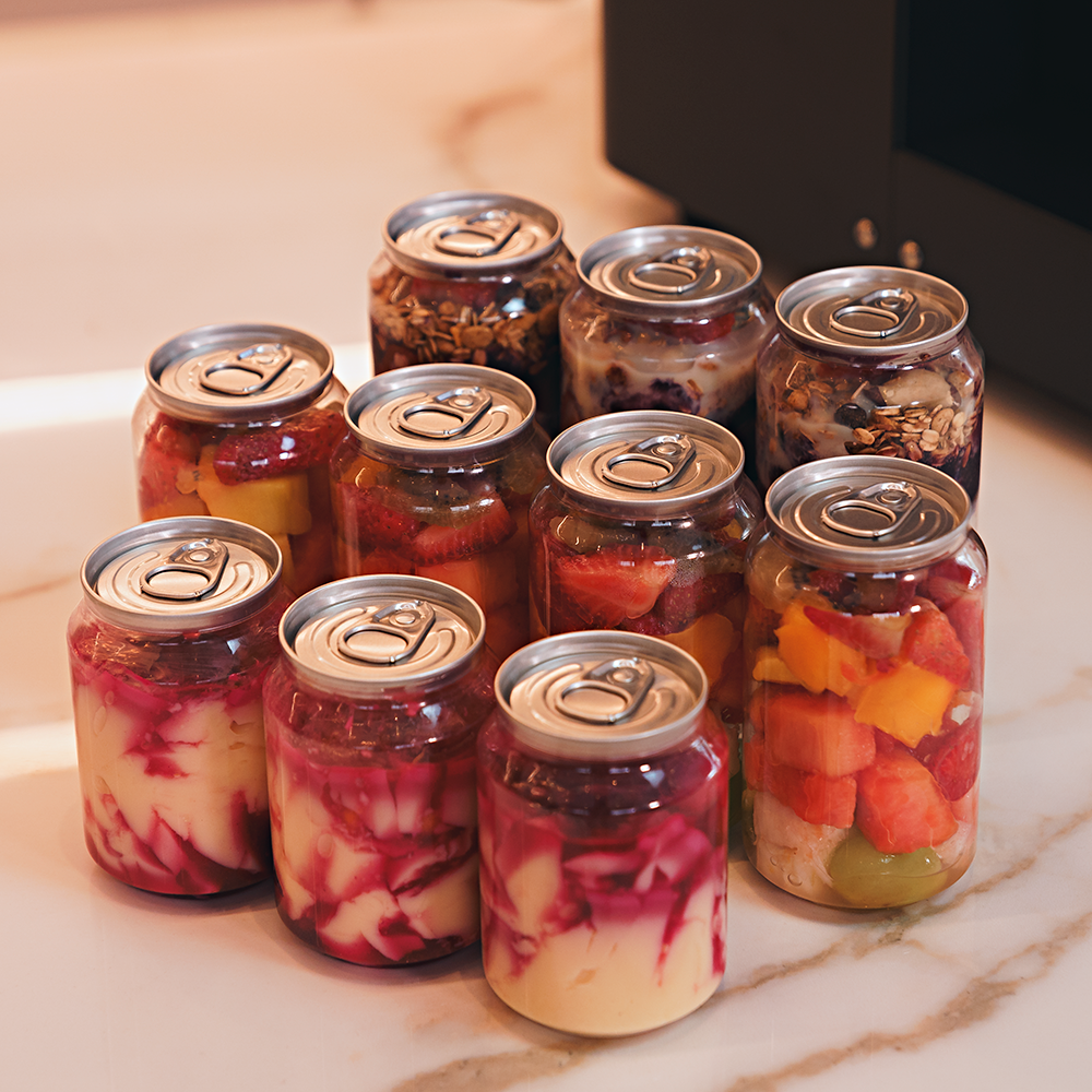 Fotografias da Seladora Recravadora de Latas Plásticas Semiautomática CCBM S-100 CS T da Cetro e de latas PET com sobremesas.