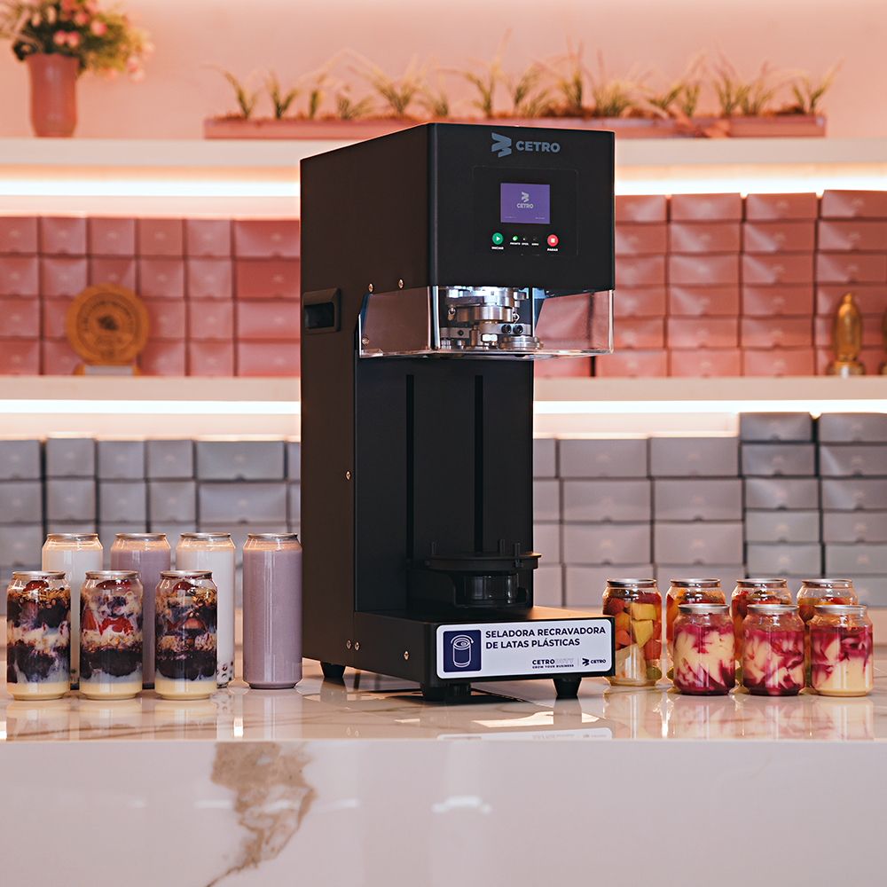 Fotografias da Seladora Recravadora de Latas Plásticas Semiautomática CCBM S-100 CS T da Cetro e de latas PET com sobremesas.