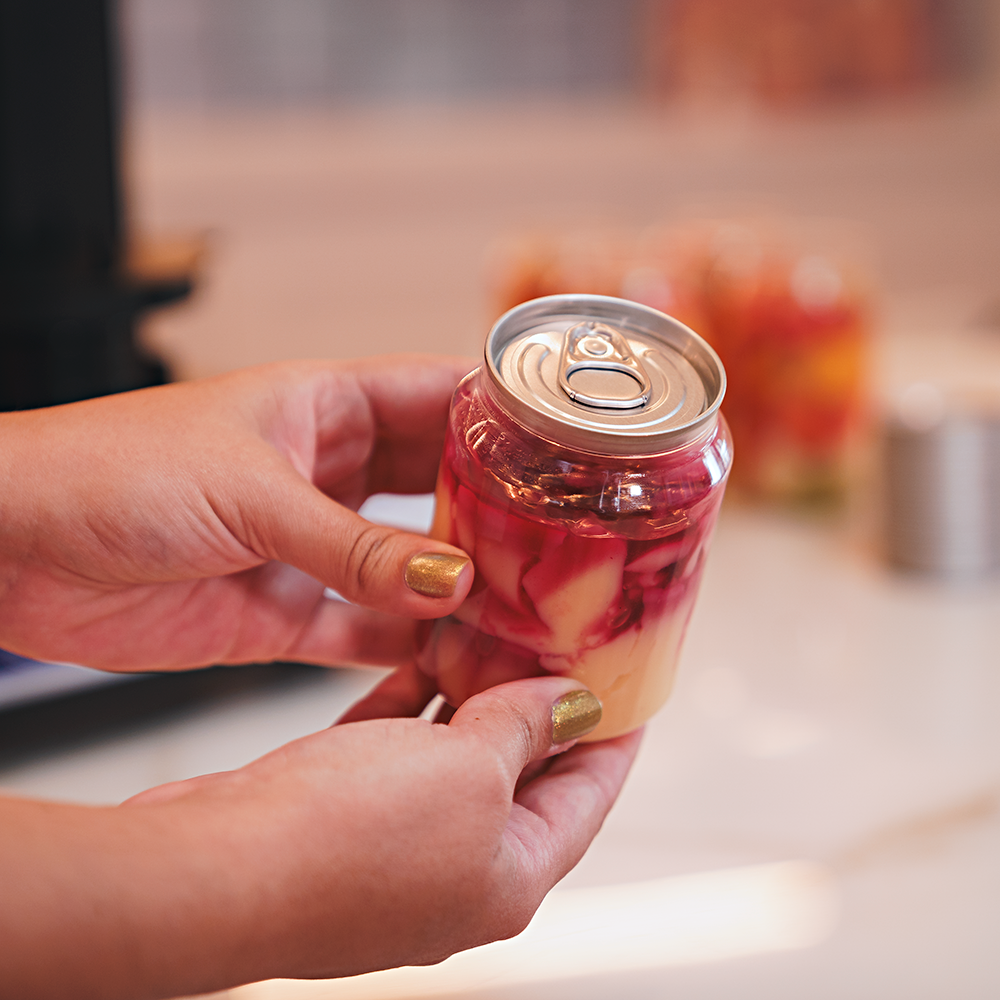 Fotografias da Seladora Recravadora de Latas Plásticas Semiautomática CCBM S-100 CS T da Cetro e de latas com sobremesas seladas por ela.