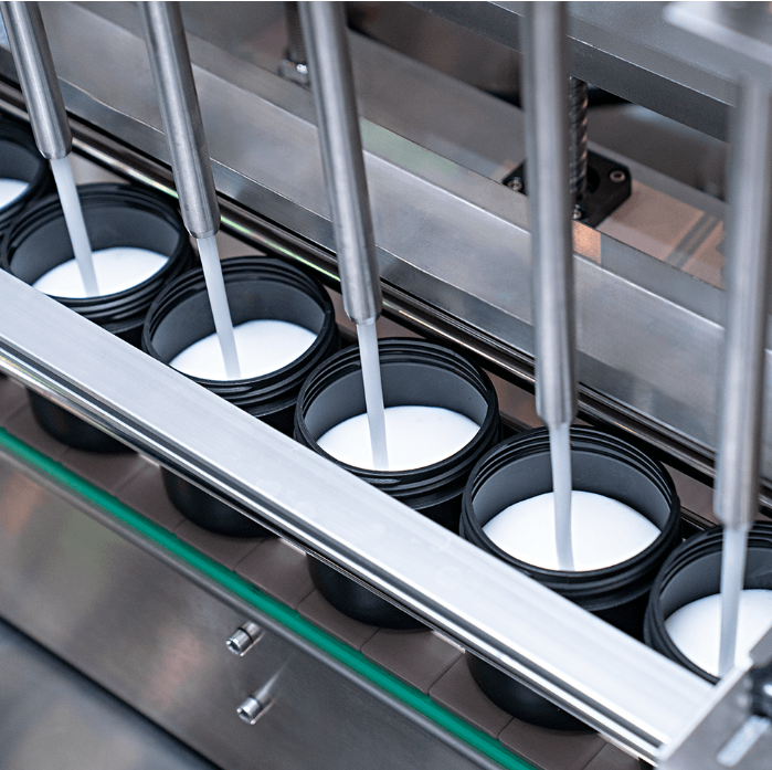 Fotografias da Envasadora Automática de Pastosos Servomotorizada CAFM VP-1000 6N SM envasando cosméticos em potes.