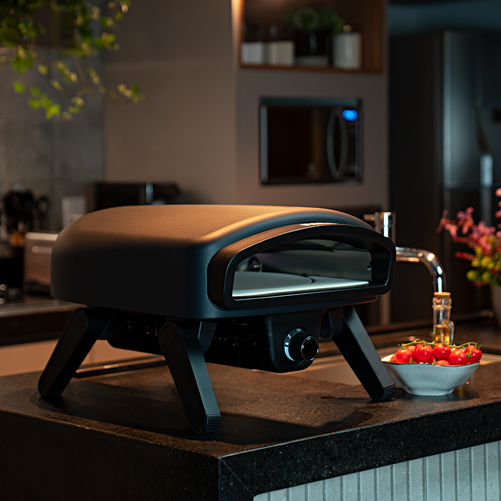 Fotografias do Forno de Pizza Nino a Gás com Pedra Redonda e Sistema Giratório CFBM PO-330 RR G assando uma pizza em uma área gourmet.