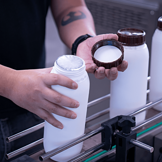 Seladora de Indução Eletromagnética Refrigerada com Esteira CASM I-150 da Cetro e um frasco selado por ela.